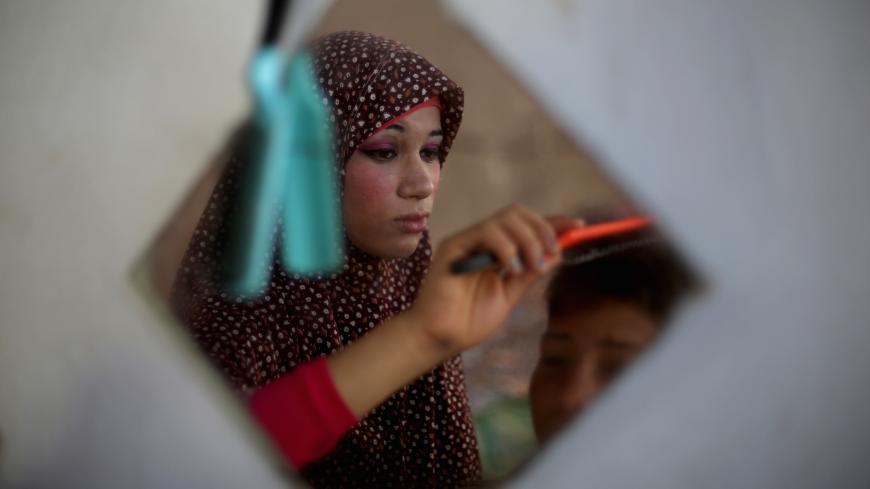 Newlywed Tala, 14, brushes the hair of her 15-year-old husband Ahmed Soboh, at their home four days after their wedding in the northern Gaza Strip town of Beit Lahia, near the border with Israel on September 28, 2013. The young couple live in the family's three-room home, sharing it with nine other relatives. Ahmed works with his father as a road cleaner earning $5 (US dollars) per day. AFP PHOTO / MOHAMMED ABED        (Photo credit should read MOHAMMED ABED/AFP/Getty Images)