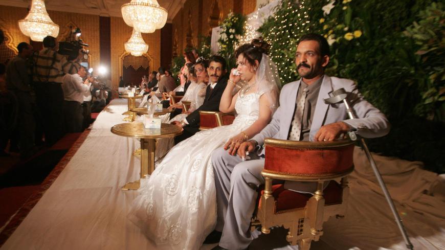 CAIRO, EGYPT:  Physically handicapped couples are seated in a straight line during a group wedding held at a five-star hotel in Cairo late 16 August 2004. Twenty disabled couples, most of them sports champions in national games for the physically challenged, celebrated together in a mass wedding party organised by the Egyptian Handicap Challengers Association.      AFP PHOTO/Marwan NAAMANI  (Photo credit should read MARWAN NAAMANI/AFP/Getty Images)