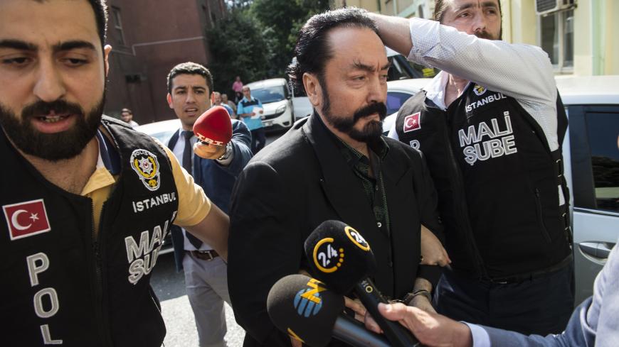 Turkish police officers escort televangelist and leader of a sect, Adnan Oktar (C) on July 11, 2018, in Istanbul, as he is arrested on fraud charges. - Turkish police detained the televangelist on fraud charges on July 11, 2018, notorious for propagating conservative views while surrounded by scantily-clad women he refers to as his "kittens". (Photo by - / DOGAN NEWS AGENCY / AFP) / Turkey OUT        (Photo credit should read -/AFP/Getty Images)