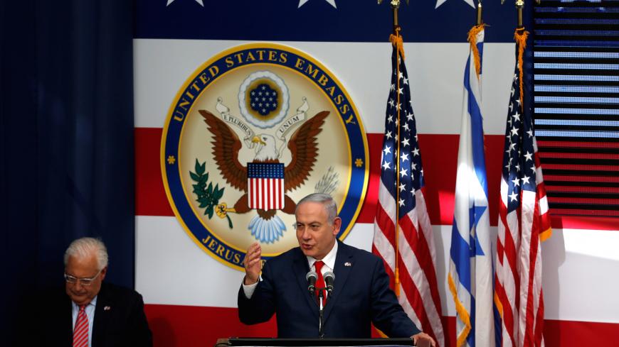 Israeli Prime Minister Benjamin Netanyahu speaks as U.S. Ambassador to Israel David Friedman sits next to him during the dedication ceremony of the new U.S. embassy in Jerusalem, May 14, 2018. REUTERS/Ronen Zvulun - RC1371421C00