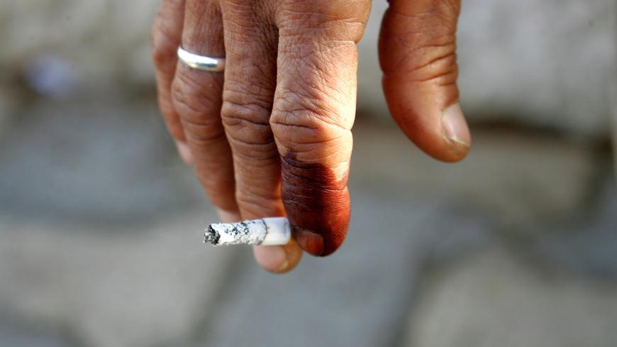 An Iraqi's ink-stained finger is seen holding on to a cigarette in Amman December 14, 2005. [Iraq's al Qaeda and other militant groups branded landmark elections as ungodly and vowed to keep up their jihad to turn the country into an Islamic state, according to an Internet statement dated Monday.] - PBEAHUNUBES