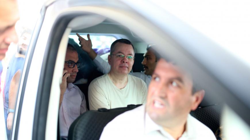 US Pastor Andrew Craig Brunson (C), is seen inside a car escorted by Turkish plain clothes police officers  as he arrives at his house on July 25, 2018 in Izmir. - A Turkish court on July 25, 2018 ruled to place under house arrest US pastor who has been imprisoned for almost two years on terror-related charges in a case that has raised tensions with the United States, state media said. The state-run Anadolu news agency said he was being put under house arrest, although it was not clear if he had already lef