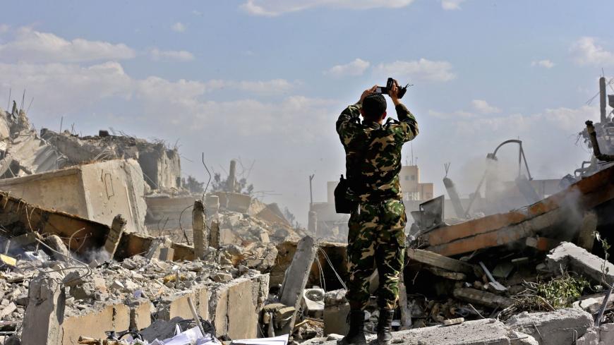 TOPSHOT - A Syrian soldier inspects the wreckage of a building described as part of the Scientific Studies and Research Centre (SSRC) compound in the Barzeh district, north of Damascus, during a press tour organised by the Syrian information ministry, on April 14, 2018. - The United States, Britain and France launched strikes against Syrian President Bashar al-Assad's regime early on April 14 in response to an alleged chemical weapons attack after mulling military action for nearly a week. Syrian state news