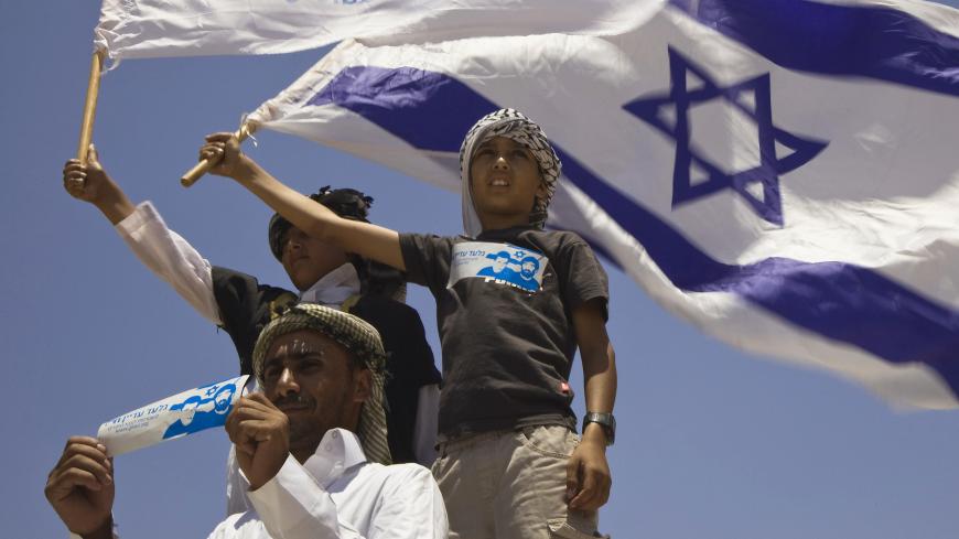 Israeli Bedouins hold flags during a rally marking the fifth anniversary of captured Israeli soldier Gilad Shalit near the southern kibbutz of Kerem Shalom June 25, 2011. The International Red Cross called on Hamas on Thursday to provide proof that Shalit is still alive nearly five years after his capture by Palestinian militants. June 25, 2011 marks the fifth anniversary of Shalit's capture. REUTERS/Amir Cohen (ISRAEL - Tags: POLITICS MILITARY CIVIL UNREST ANNIVERSARY) - GM1E76P1TT401