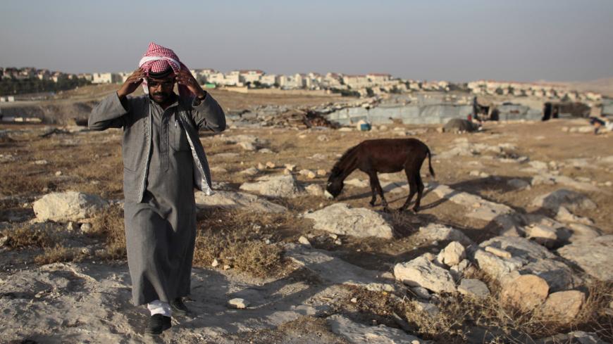 A Bedouin of the Jahalin tribe walks in his encampment near the Jewish settlement of Maale Adumim (seen in the background), east of Jerusalem June 16, 2012. Bedouin tents and wandering goats dot the barren hills on the drive from Jerusalem down to the Dead Sea. But the Bedouin tradition is slowly dying out as Israel clears the camps to make way for expanding Jewish urban settlements. Picture taken June 16, 2012. To match Feature PALESTINIANS-ISRAEL/BEDOUIN       REUTERS/Ammar Awad (JERUSALEM - Tags: SOCIETY