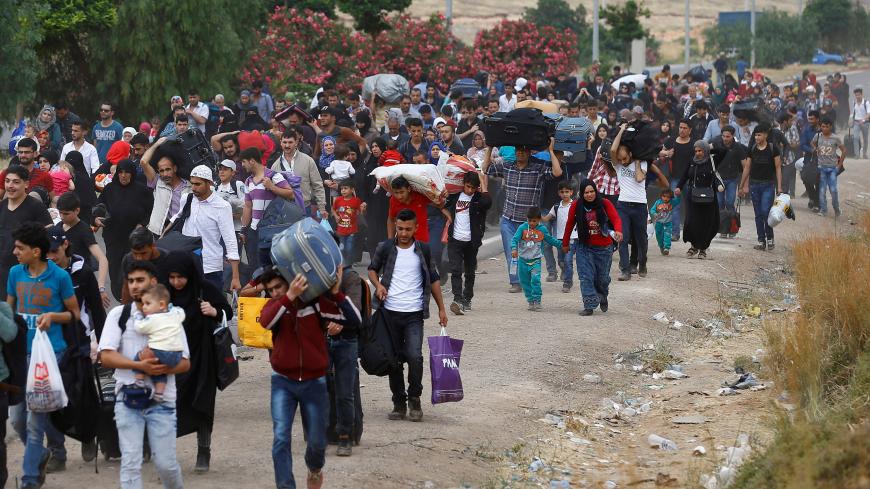 Syrians, who say they are returning to Syria ahead of Eid al-Fitr, carry their belongings as they walk to the Turkish Cilvegozu border gate located opposite of the Syrian crossing point of Bab al-Hawa in Reyhanli, in the southern Hatay province, Turkey June 14, 2017. REUTERS/Umit Bektas - RC126797B440