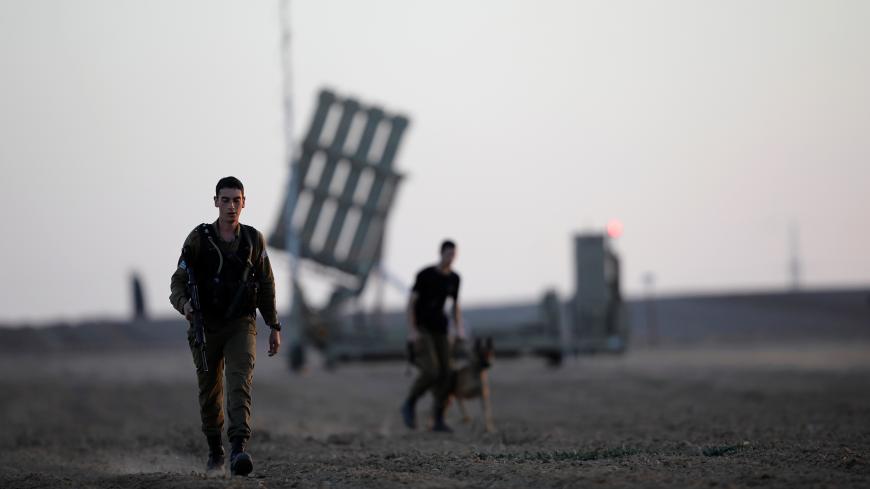 Israeli soldiers walk past an Iron Dome rocket interceptor battery deployed near central Gaza Strip, southern Israel October 31, 2017. REUTERS/Amir Cohen - RC173427FF50