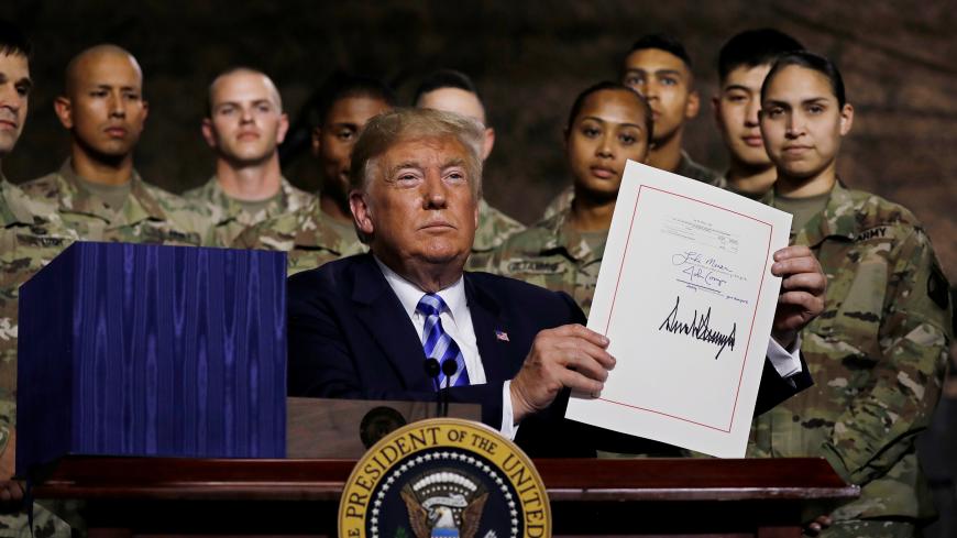 U.S. President Donald Trump holds up the National Defense Authorization Act after signing it in front of soldiers from the U.S. Army's 10th Mountain Division at Fort Drum, New York, U.S., August 13, 2018. REUTERS/Carlos Barria - RC1992081BA0