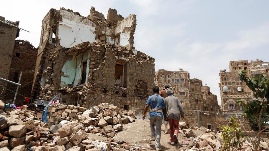 People walk past a house destroyed by an air strike in the old quarter of Sanaa, Yemen August 8, 2018. Picture taken August 8, 2018. REUTERS/Khaled Abdullah - RC1116261260