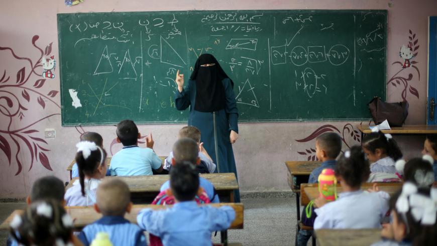 A veiled Palestinian teacher gives a mathematics lesson for schoolchildren in a classroom on the first day of a new school year, at a United Nations-run school in Khan Young in the southern Gaza Strip August 28, 2016. REUTERS/Ibraheem Abu Mustafa  - S1AETXZTHIAA