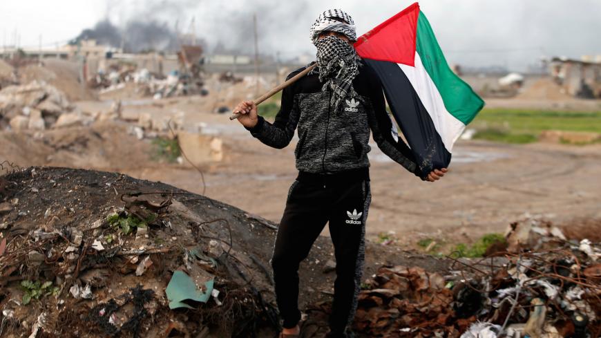 A protester holds a Palestinian flag as he poses for a photograph at the scene of clashes with Israeli troops near the border with Israel, east of Gaza City, January 19, 2018. "The battle between us and the Israeli occupation has been ongoing for decades. We will continue to protest and resist as long as there is one Israeli occupier on our land. Trump and anyone else in this world will not be able to control our anger," he said. REUTERS/Mohammed Salem        SEARCH "PROTESTER PALESTINIAN" FOR THIS STORY. S