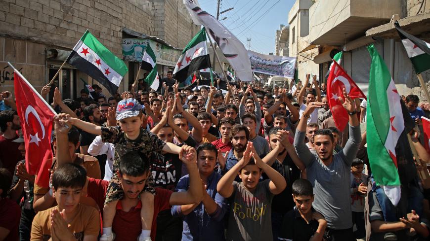 Syrians chant slogans as they wave flags of the opposition and of Turkey during a demonstration against the Syrian government in the rebel-held town of Hazzanu, about 20 kilometres northwest of the city of Idlib, on September 21, 2018. (Photo by Aaref WATAD / AFP)        (Photo credit should read AAREF WATAD/AFP/Getty Images)