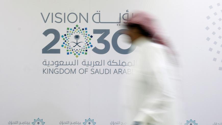A man walks past the logo of Vision 2030 after a news conference, in Jeddah, Saudi Arabia June 7, 2016. REUTERS/Faisal Al Nasser/File Photo - S1AETISGXVAA
