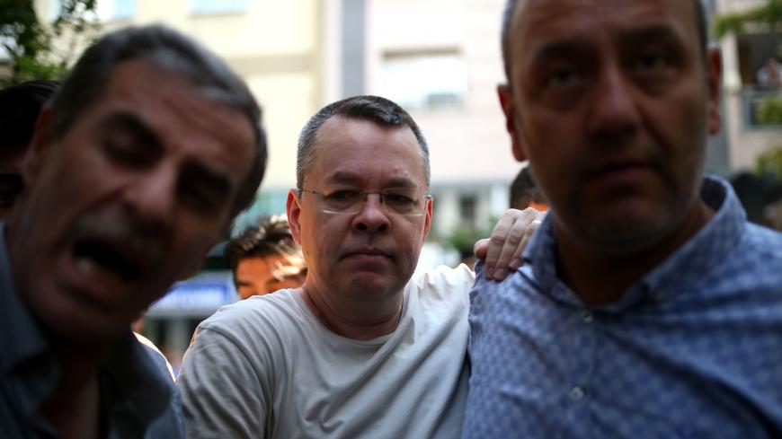 US Pastor Andrew Craig Brunson (C), is seen inside a car escorted by Turkish plain clothes police officers  as he arrives at his house on July 25, 2018 in Izmir. - A Turkish court on July 25, 2018 ruled to place under house arrest US pastor who has been imprisoned for almost two years on terror-related charges in a case that has raised tensions with the United States, state media said. The state-run Anadolu news agency said he was being put under house arrest, although it was not clear if he had already lef