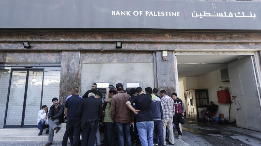 Palestinian employees queue outside a cash machine outside the Bank of Palestine as they wait to withdraw their salaries, in Gaza City on April 9, 2018. (Photo by MAHMUD HAMS / AFP)        (Photo credit should read MAHMUD HAMS/AFP/Getty Images)
