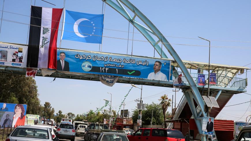 A picture taken on April 30, 2018 shows an electoral banner for the Iraqi Turkmen Front hanging beneath the flags of Iraq (L) and the Iraqi Turkmen (C, white crescent and stars on a blue background) above a pedestrian crossing in the oil-rich and multi-ethnic northern city of Kirkuk. - The past seven months have seen a dramatic turn of events in Kirkuk, the "Jerusalem of Kurdistan", where hopes of independence for Iraqi Kurdistan were dashed after Baghdad retaliated against a referendum held in September. (