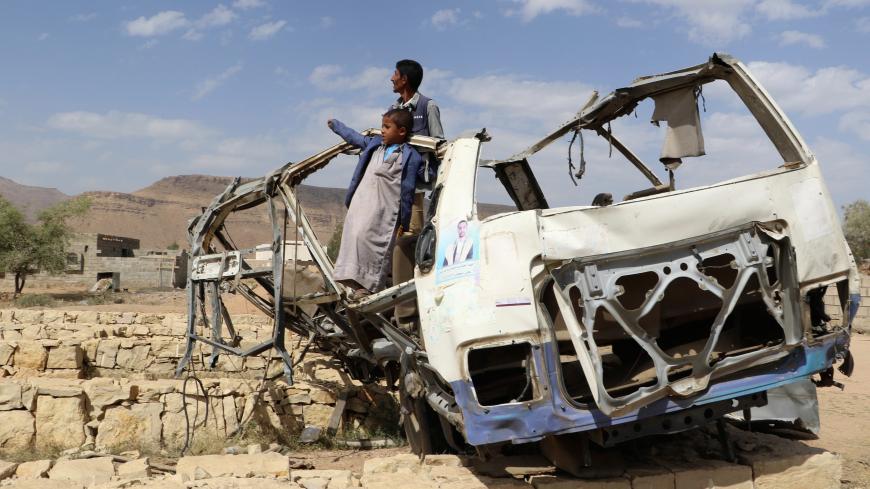 Abdullah al-Khawlani stands with his son, Hafidh, who survived a Saudi-led air strike stand on the wreckage of a bus destroyed by the strike in Saada, Yemen September 4, 2018. Another son of al-Khawlani was killed by the strike. Picture taken September 4, 2018. REUTERS/Naif Rahma - RC1F0E3F8DD0