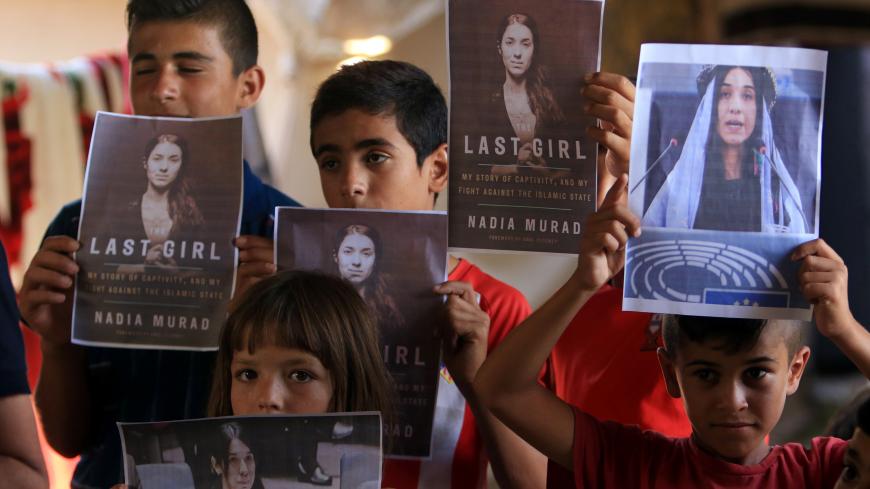 Yazidi children hold pictures of Nadia Murad, who won the Nobel Peace prize, in Duhok, Iraq October 5, 2018. REUTERS/Ari Jalal - RC1A9917F900
