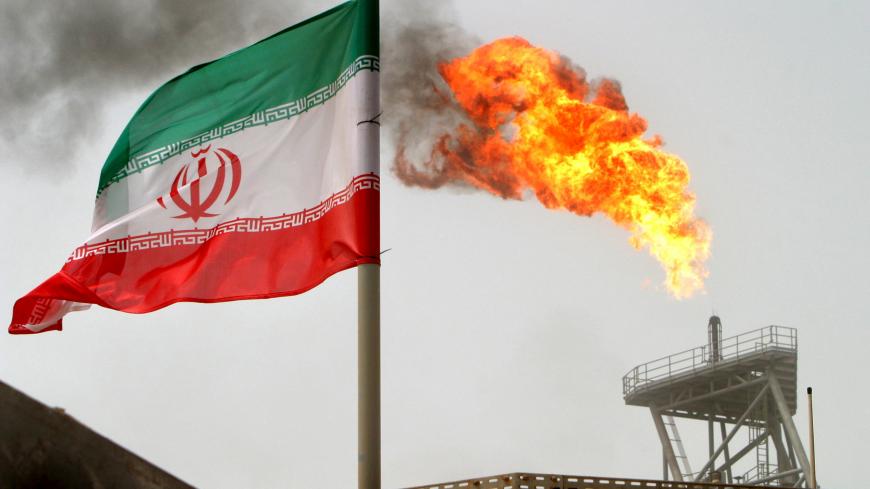 gas flare on an oil production platform in the Soroush oil fields is seen alongside an Iranian flag in the Gulf July 25, 2005. REUTERS/Raheb Homavandi/File Photo    - S1BEUEUZEDAB