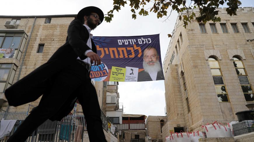 A campaign poster depicting ultra-Orthodox Jewish candidate in Jerusalem's mayoral election Yossi Daitsh is seen between buildings as an ultra-Orthodox man walks past, in Jerusalem October 18, 2018. REUTERS/Ammar Awad - RC11A312FA80