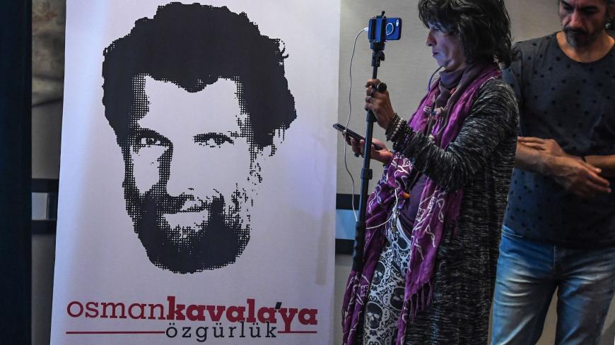 A journalist stands in front of a poster featuring jailed businessman and philanthropist Osman Kavala during a press conference of his lawyers on October 31, 2018. - Osman Kavala was arrested a year ago by Turkish authorities and has still to be charged with an offence. (Photo by OZAN KOSE / AFP)        (Photo credit should read OZAN KOSE/AFP/Getty Images)