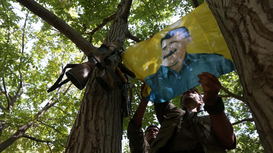 A member of the anti-Iranian group, Kurdistan Free Life Party (PJAK), hangs up a flag of jailed Kurdistan Workers' Party (PKK) leader, Abdullah Ocalan, at their base deep on the Iraq-Iran border of northern Iraq's Kurdish autonomous region, on August 28, 2017. / AFP PHOTO / SAFIN HAMED        (Photo credit should read SAFIN HAMED/AFP/Getty Images)
