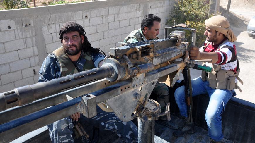 Syrian soldiers and pro-regime militiamen man a heavy machine-gun mounted on the back of a pickup truck as they ride in the recently retaken desert town of Al-Qaryatain on October 26, 2017.
The Syrian Observatory for Human Rights, a Britain-based monitor, reported on October 23, 2017 that Islamic State (IS) group militants massacred more than 100 people in the desert town of Al-Qaryatain during the month before they lost it to regime forces.
Before the civil war broke out in 2011, al-Qaryatain was a symbol 