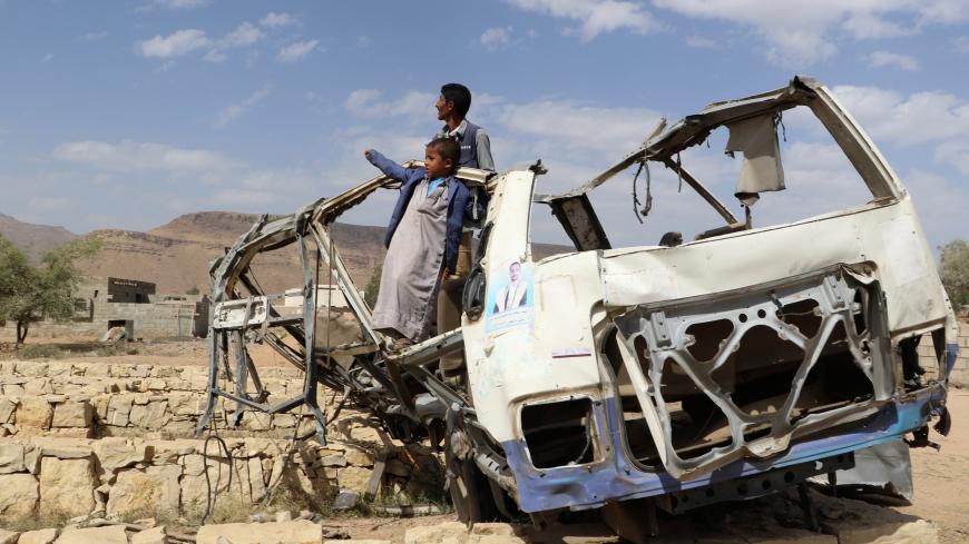 Abdullah al-Khawlani stands with his son, Hafidh, who survived a Saudi-led air strike stand on the wreckage of a bus destroyed by the strike in Saada, Yemen September 4, 2018. Another son of al-Khawlani was killed by the strike. Picture taken September 4, 2018. REUTERS/Naif Rahma - RC1F0E3F8DD0