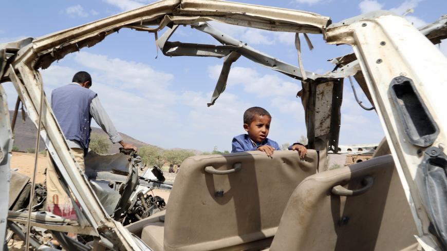 Hafidh Abdullah al-Khawlani, who survived a Saudi-led air strike stands with his father on the wreckage of a bus destroyed by the strike in Saada, Yemen September 4, 2018. His brother was killed by the air strike. Picture taken September 4, 2018. REUTERS/Naif Rahma - RC1FB49D40C0
