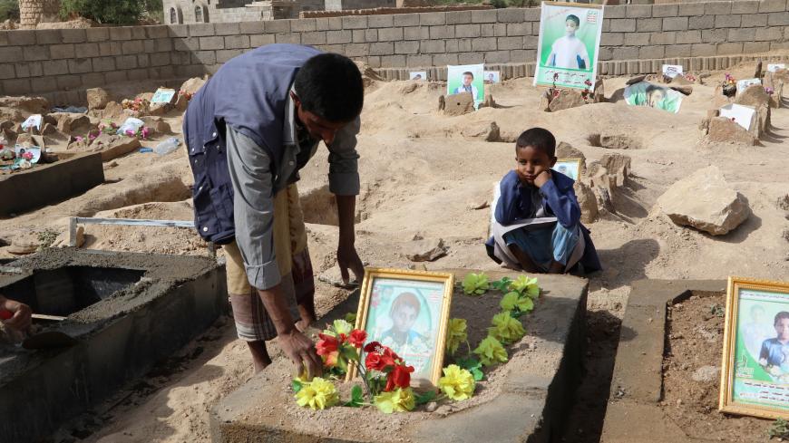 Abdullah al-Khawlani puts roses on the grave of his son, Waleed, who was killed by last month's Saudi-led air strike that killed dozens including children in Saada, Yemen September 4, 2018. His other son, Hafidh, who survived the strike, looks on. Picture taken September 4, 2018. REUTERS/Naif Rahma - RC164F27C730