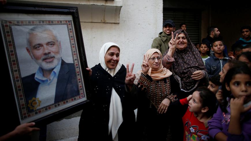 Palestinians celebrate the resignation of Israel's Defence Minister Avigdor Lieberman as a woman holds a picture of Hamas Chief Ismail Haniyeh, in Gaza City November 14, 2018. REUTERS/Suhaib Salem - RC1BF0D8E8D0