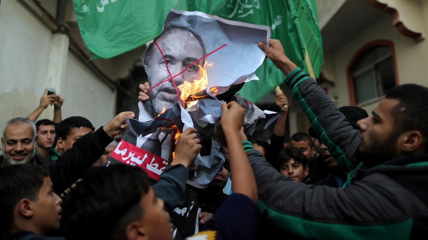 Palestinians burn a poster depicting Israel's Defence Minister Avigdor Lieberman as they celebrate after Lieberman announced his resignation, in Gaza City November 14, 2018. REUTERS/Suhaib Salem        TPX IMAGES OF THE DAY - RC154FC040F0