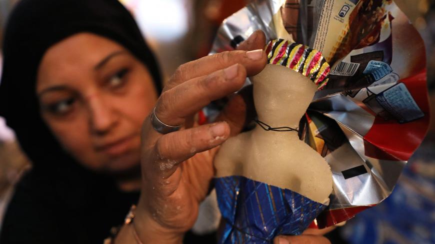 A woman decorates traditional sugar candy in the shape of a doll at a street market ahead of Mawlid al-Nabi, the birthday of Prophet Mohammad, in Cairo, Egypt November 12, 2018. Picture taken November 12, 2018. REUTERS/Mohamed Abd El Ghany - RC12462B4D90