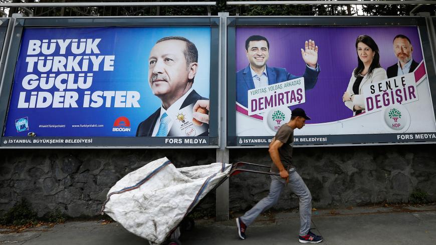 A garbage collector walks past election posters for Turkey's President Tayyip Erdogan (L) and Turkey's main pro-Kurdish Peoples' Democratic Party (HDP) jailed former leader and presidential candidate Selahattin Demirtas in Istanbul, Turkey, June 19, 2018. Left poster reads, "Turkey requires a strong leader". Right poster reads, "It changes with you".  REUTERS/Huseyin Aldemir - RC1A01DA8990