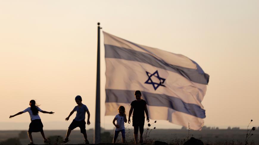 Israeli kids play next to an Israeli flag next to the Israeli Syrian border at the Israeli-occupied Golan Heights, Israel July 23, 2018. REUTERS/Ronen Zvulun - RC179A5708F0