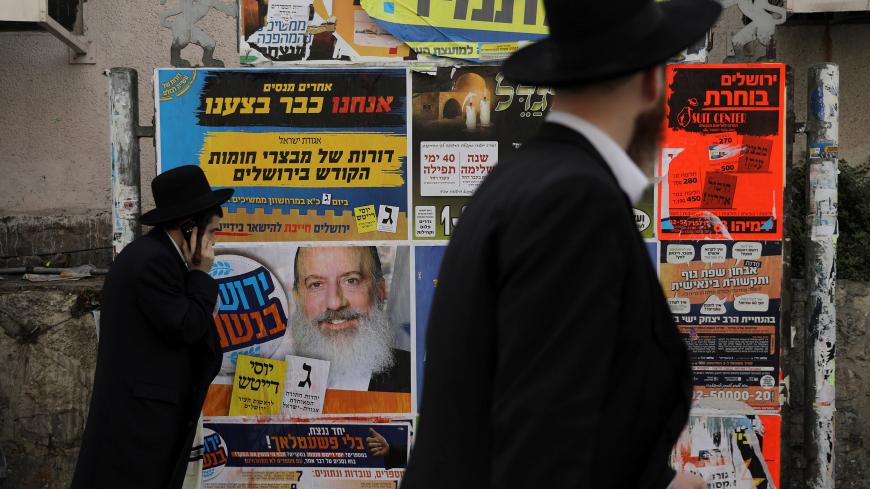 Ultra-Orthodox Jewish men walk past a campaign poster depicting ultra-Orthodox Jewish candidate in Jerusalem's mayoral election Yossi Daitsh, in Jerusalem October 18, 2018. REUTERS/Ammar Awad - RC1A4B7FF670
