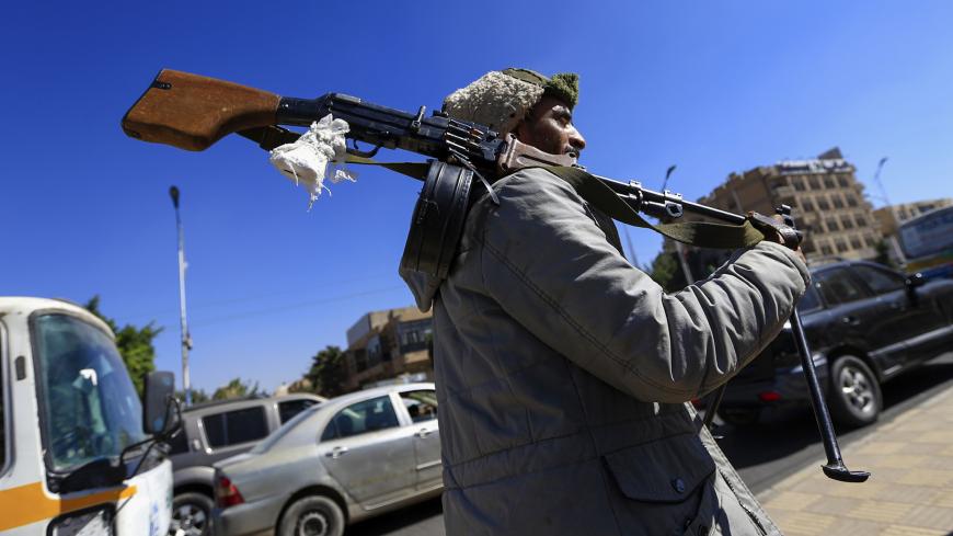 A Huthi rebel fighter carries a machine gun on his shoulder during a protest outside the United Nations office demanding the reopening of Sanaa airport, in the Yemeni capital Sanaa on December 10, 2018. - Yemen's foreign minister said on December 8 that the government-controlled city of Aden could be home to the country's main airport, amid talks to reopen the rebel-held international airport in the capital Sanaa which has been out of operation for years, after being severely damaged in air raids by the Sau