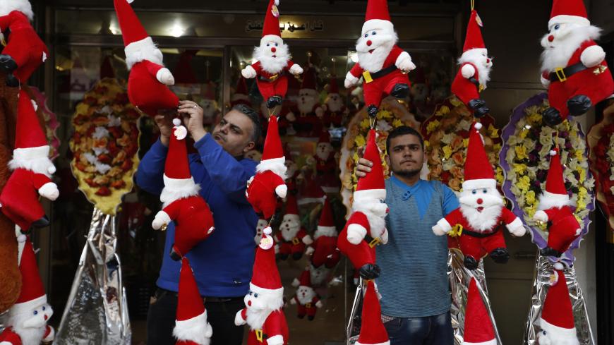 Palestinian shopkeepers decorate their stand with toys of Father Christmas in Gaza City on December 24, 2014, as Christians around the world prepare to celebrate Christmas. For many faithful across the region, the festivities will be tinged with sadness following a year of bloodshed marked by a surge in the persecution of Christians that has drawn international condemnation. AFP PHOTO / MOHAMMED ABED        (Photo credit should read MOHAMMED ABED/AFP/Getty Images)