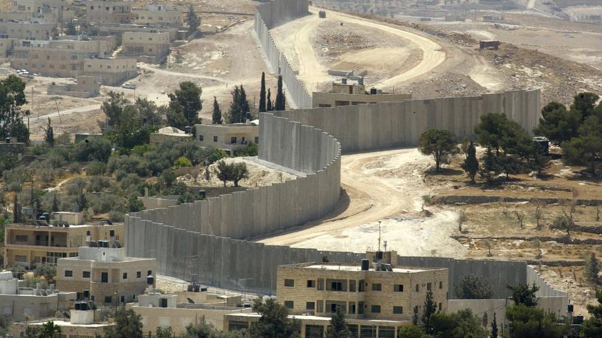 A general view shows the concrete wall, part of Israel's controversial security barrier, which seperates the eastern neighbourhoods of Jerusalem from the West Bank town of Abu Dis (L) July 16, 2004.The U.N. General Assembly is drawing up a draft resolution demanding that Israel obey a World Court ruling and tear down its West Bank wall as Israeli Tourism Minister Gideon Ezra was quoted as saying that it should be turned into a must-see tourist attraction to help visitors understand the country's security pr