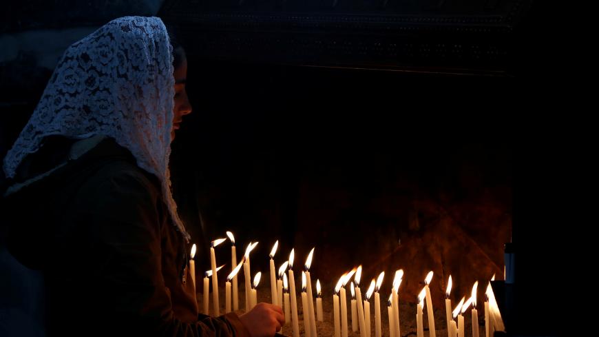 A Christian worshipper lights candles following a mass on Christmas at the Virgin Mary Syriac Orthodox Church in Diyarbakir, Turkey, December 25, 2017. REUTERS/Sertac Kayar - RC11AF1EE450