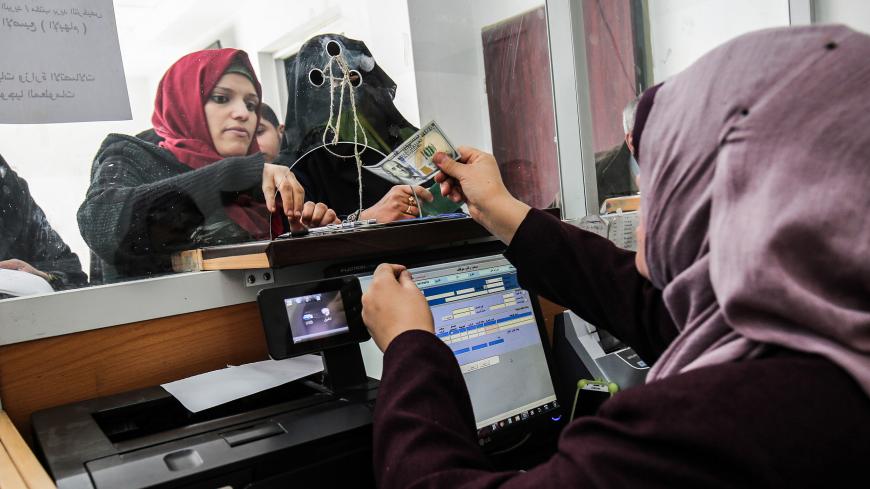 A Palestinian government employee receives a portion her his overdue salary at a post office in Rafah in the southern Gaza Strip on December 8, 2018, after the Hamas-run finance ministry had announced that the money would be distributed over the two days, with employees receiving 50 percent of their salaries. - Employees of the Hamas administration in the Gaza Strip began collecting their salaries for a second month on December 7, after Qatar pumped more money into the territory with Israel's blessings. The
