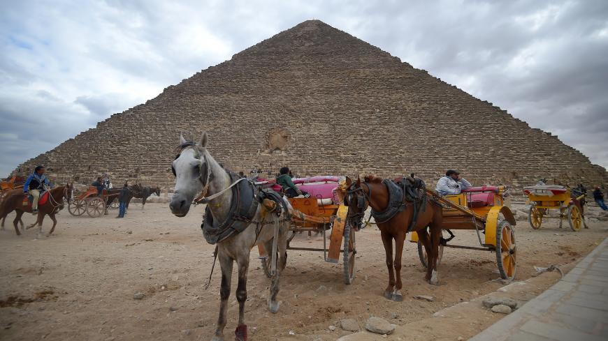 This picture taken on December 29, 2018 shows tourist horse-drawn carts waiting by the base of the Great Pyramid of Khufu (or Cheops) at the Giza necropolis on the southwestern outskirts of the Egyptian capital Cairo on December 29, 2018. (Photo by MOHAMED EL-SHAHED / AFP)        (Photo credit should read MOHAMED EL-SHAHED/AFP/Getty Images)