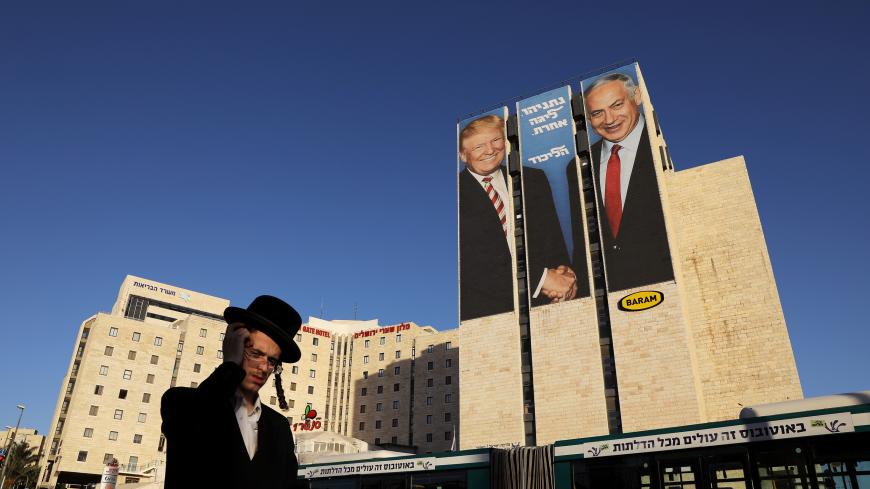 A man walks past a Likud election campaign billboard, depicting U.S. President Donald Trump shaking hands with Israeli Prime Minister Benjamin Netanyahu, in Jerusalem February 4, 2019. REUTERS/Ammar Awad - RC1275660830