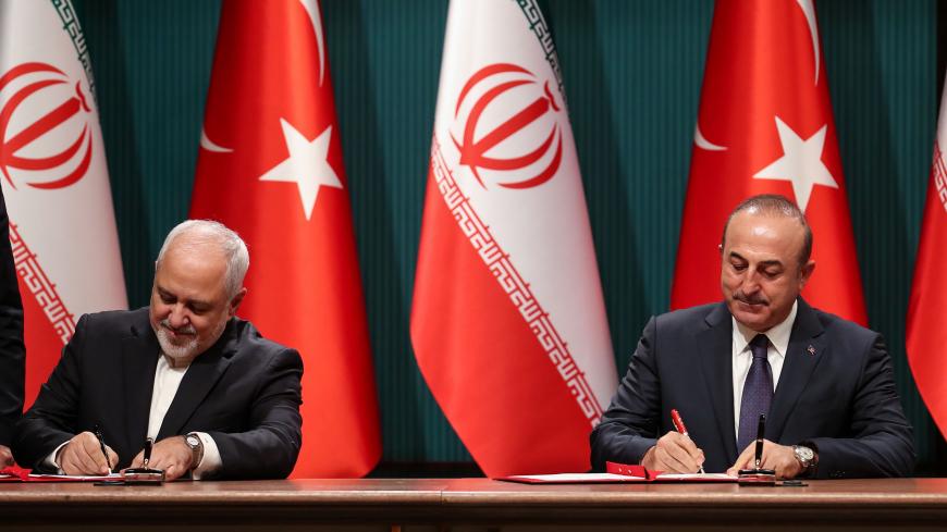Iranian Foreign Minister Javad Zarif (L) and Turkish Foreign Minister Mevlut Cavusoglu (R) sign a cooperation agreement before a joint press conference with Turkey's President and Iran's President at the Turkish presidential complex in Ankara on December 20, 2018. - The Turkish President held talks with Rouhani with Syria likely to dominate the agenda after the surprise US decision to withdraw. The meeting in Ankara had been arranged before US President stunned allies and American officials the day before w
