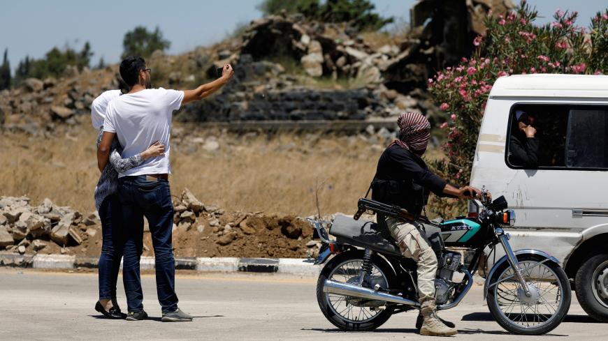 A rebel fighter rides on a motorbike as people take a selfie on a road in Quneitra, Syria July 27, 2018. REUTERS/Omar Sanadiki - RC1305C71BB0