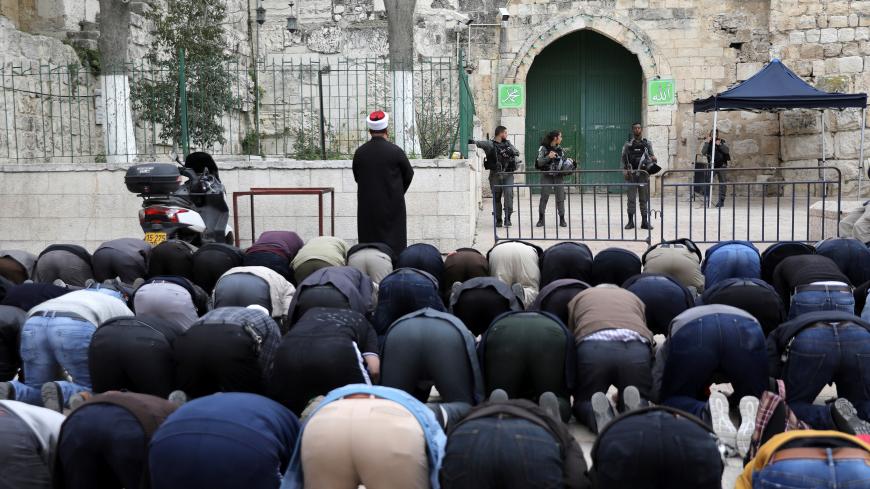 Palestinians pray as Israeli border police stand guard near the entrance door leading to the compound housing al-Aqsa Mosque in Jerusalem's Old City March 12, 2019. REUTERS/Ammar Awad - RC1CD60A6C60