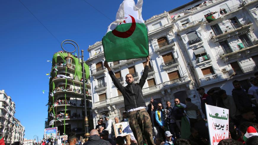 A demonstrator carries a national flag during protest over President Abdelaziz Bouteflika's decision to postpone elections and extend his fourth term in office, in Algiers, Algeria March 15, 2019.REUTERS/Ramzi Boudina - RC1EA91C6690