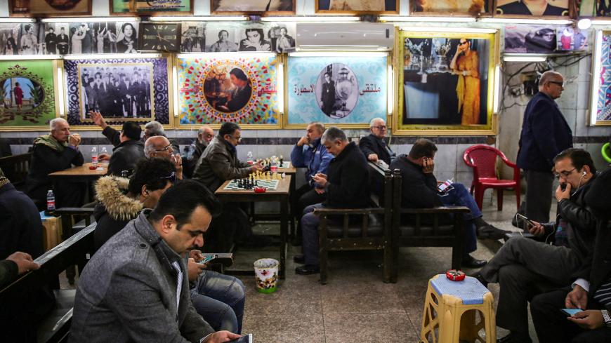 Iraqi men gather and socialise at Umm Kulthum Cafe on Rasheed street, the oldest street in the capital Baghdad on January 20, 2019. - Behind the dilapidated storefronts and collapsing colonnades of Rasheed Street lie the treasures of the Iraqi capital's cultural boom years but with young Iraqis listening to modern music and spending hours in hipster-style coffee shops, the boulevard that bustled non-stop in the 1970s is at risk of being passed over. (Photo by SABAH ARAR / AFP)        (Photo credit should re
