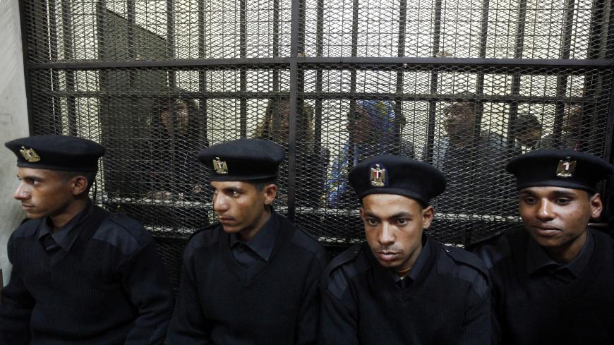 Some of the fourteen Egyptian activists who were accused of working for unlicensed non-governmental organizations (NGOs) and receiving illegal foreign funds, stand in a cage during the opening of their trial in Cairo February 26, 2012. An Egyptian court adjourned the trial of dozens of democracy activists including 16 Americans on Sunday at the opening session of a case that has threatened ties between Cairo and Washington and $1.3 billion in annual U.S. military aid. REUTERS/Mohamed Abd El Ghany  (EGYPT - 