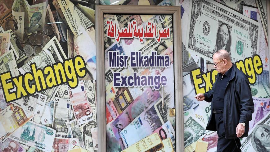 A man walks past a currency exchange bureau advertisement showing images of the U.S. dollar and other currencies in Cairo, Egypt, April 2, 2019. REUTERS/Mohamed Abd El Ghany - RC1BF9442E80